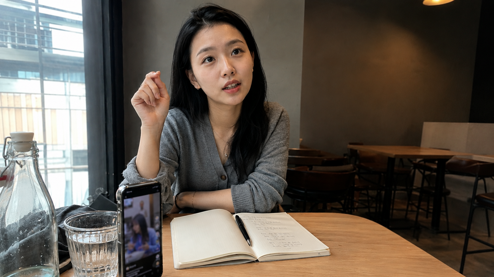 Young producer learning microdrama terms with a notebook and a vertical video playing on her phone